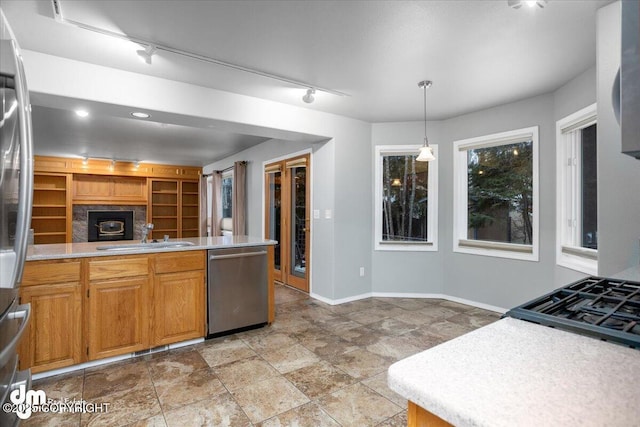 kitchen featuring a sink, light countertops, track lighting, pendant lighting, and stainless steel dishwasher