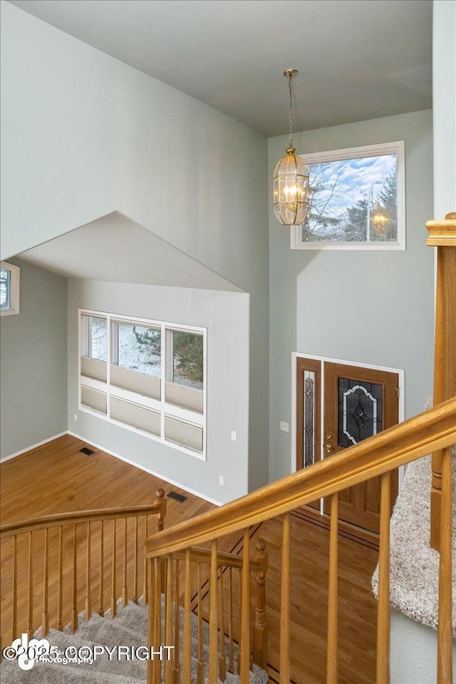 interior space with wood finished floors, a healthy amount of sunlight, a chandelier, and stairs