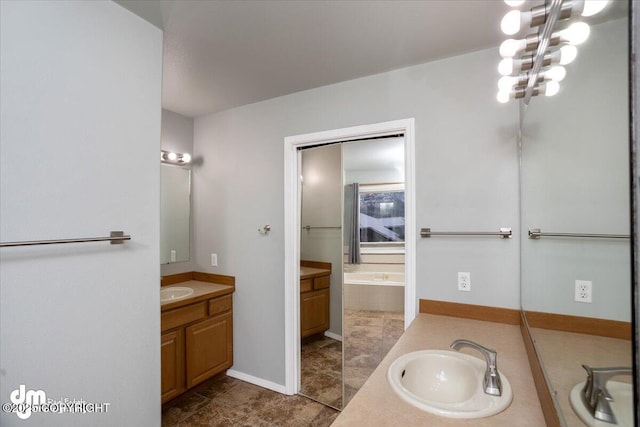 full bathroom with vanity, a bath, and baseboards