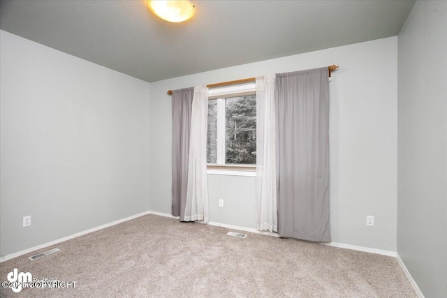 spare room with carpet flooring, baseboards, and visible vents