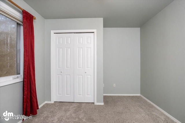 unfurnished bedroom featuring a closet, carpet flooring, and baseboards