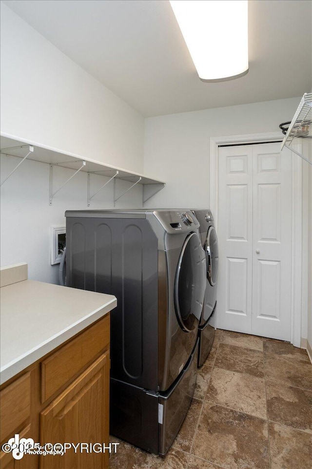 clothes washing area featuring washing machine and dryer, laundry area, and stone finish floor