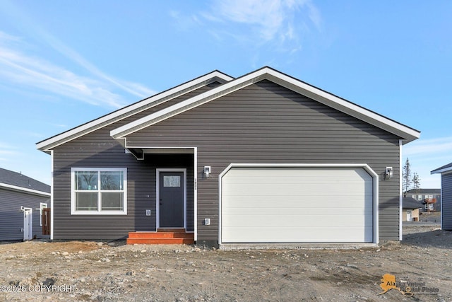 view of front of home featuring an attached garage and dirt driveway