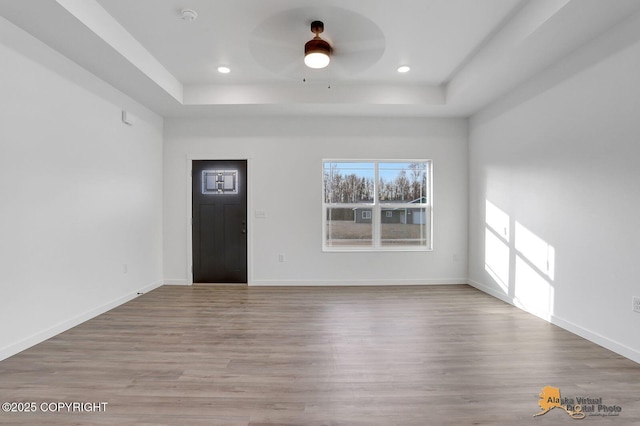 foyer entrance with ceiling fan, baseboards, a tray ceiling, and wood finished floors