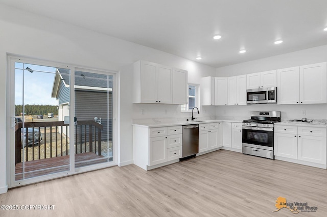 kitchen with recessed lighting, light wood-style flooring, appliances with stainless steel finishes, white cabinets, and a sink