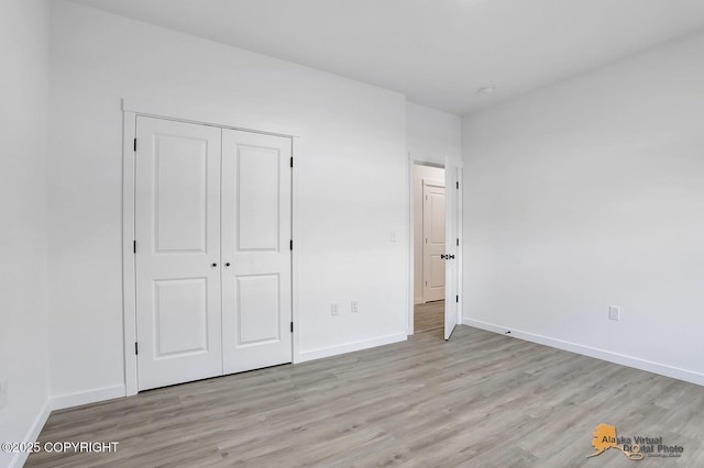 unfurnished bedroom with light wood-type flooring, baseboards, and a closet