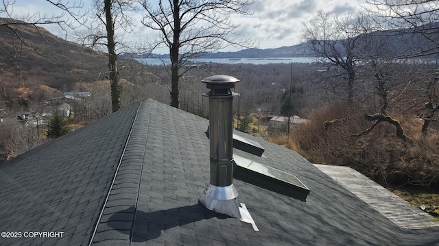 details featuring a shingled roof, a chimney, and a mountain view