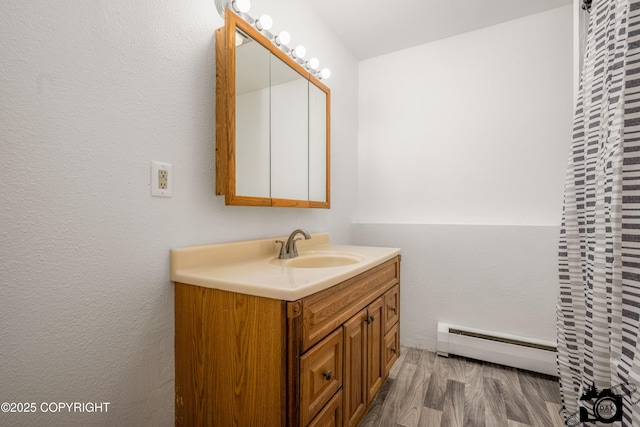 bathroom featuring vanity, a baseboard heating unit, and wood finished floors