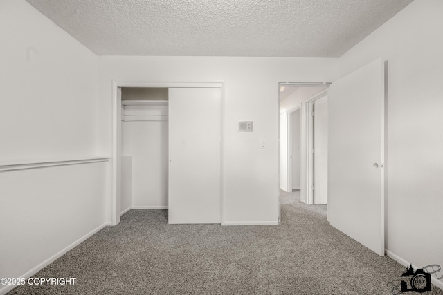 unfurnished bedroom featuring a closet, a textured ceiling, baseboards, and carpet floors