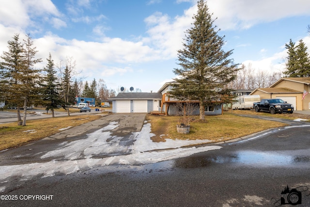 view of front of home featuring aphalt driveway, a garage, and a front lawn