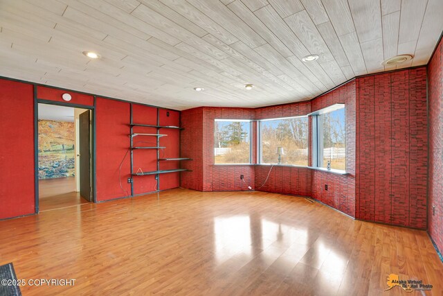 empty room with wood finished floors and brick wall
