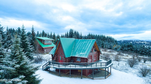 snow covered rear of property with log siding, metal roof, and a deck