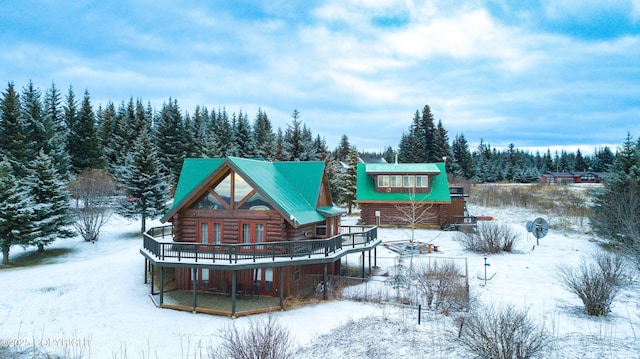 snow covered rear of property featuring log siding and a wooden deck