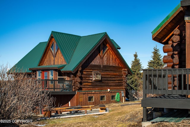 back of house featuring a barn, log siding, and metal roof