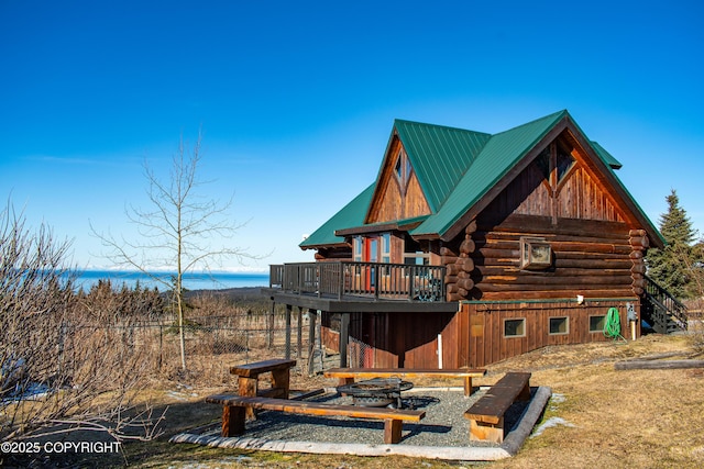 back of property with a barn, log exterior, a water view, and metal roof