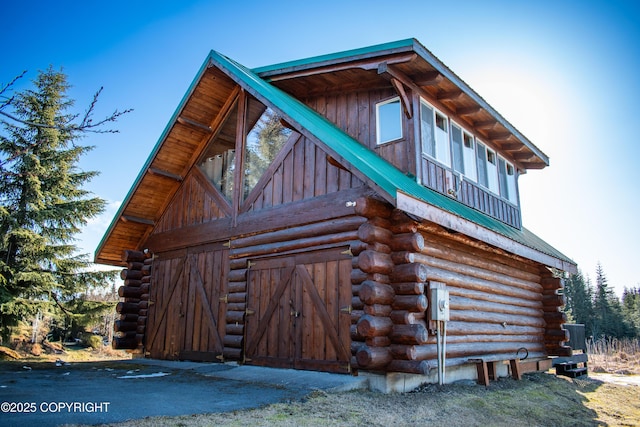 view of home's exterior featuring a barn, log siding, an outdoor structure, and metal roof