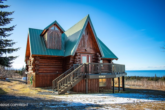 log home featuring metal roof, a deck with water view, log exterior, and stairway