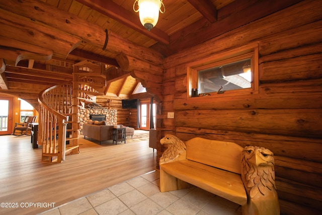 sitting room featuring beam ceiling, arched walkways, a stone fireplace, wooden ceiling, and rustic walls