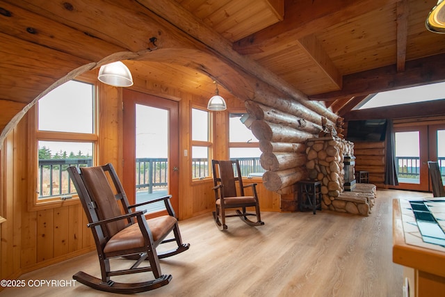 sitting room featuring wood finished floors, french doors, a stone fireplace, wood ceiling, and vaulted ceiling with beams