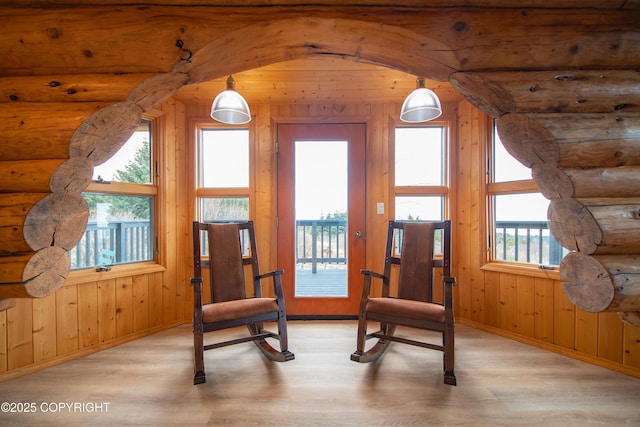 living area with rustic walls, baseboards, and wood finished floors