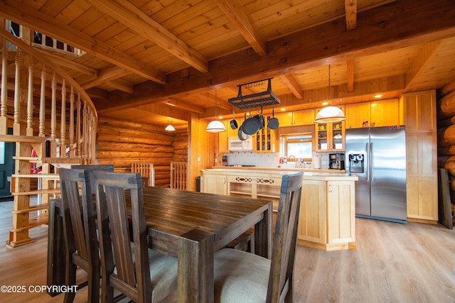 dining room featuring rustic walls, beamed ceiling, wooden ceiling, and light wood-type flooring