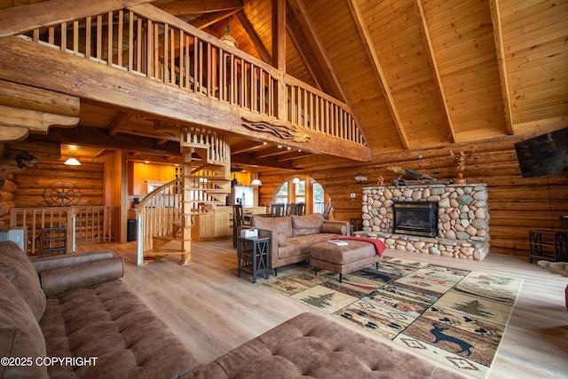 unfurnished living room featuring beamed ceiling, wood finished floors, wooden ceiling, a fireplace, and stairs