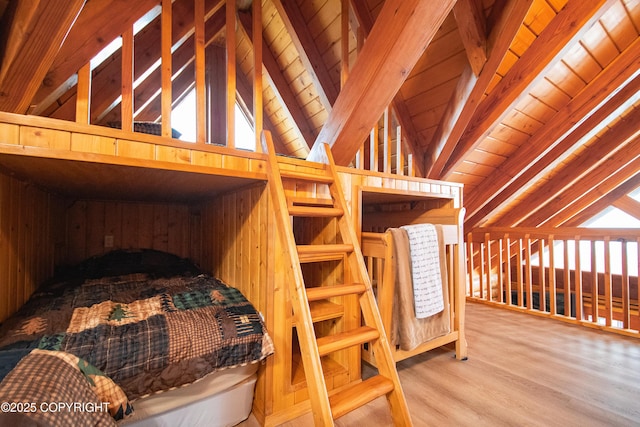 bedroom with wood finished floors, vaulted ceiling with beams, wood ceiling, and wood walls