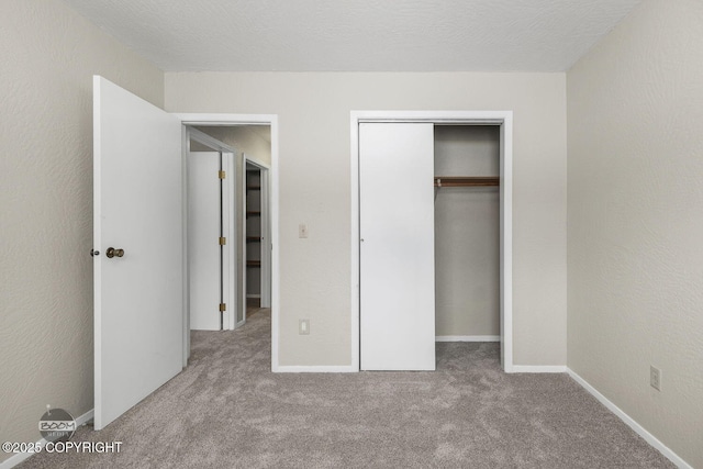 unfurnished bedroom with a closet, carpet floors, baseboards, and a textured wall