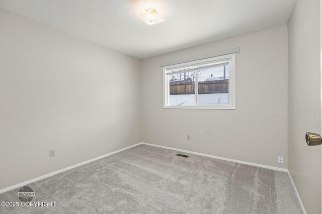 carpeted spare room with baseboards, visible vents, a textured wall, and a textured ceiling