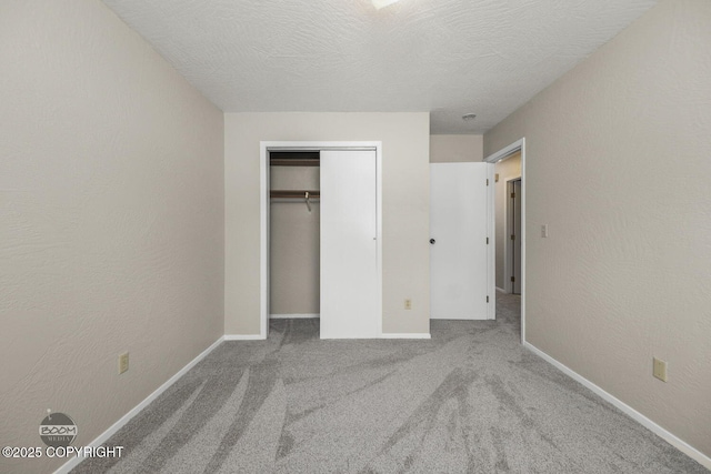 unfurnished bedroom featuring baseboards, carpet flooring, a textured wall, a closet, and a textured ceiling