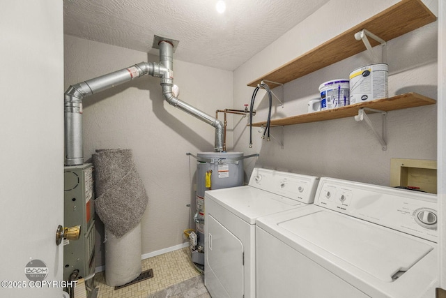 clothes washing area with washing machine and clothes dryer, baseboards, gas water heater, laundry area, and a textured ceiling