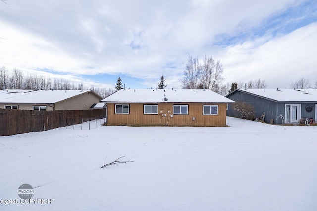 snow covered rear of property with fence