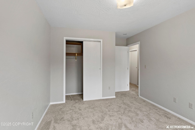 unfurnished bedroom with carpet floors, baseboards, a closet, and a textured ceiling