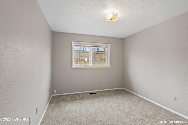 unfurnished room with baseboards, carpet, a textured ceiling, and visible vents