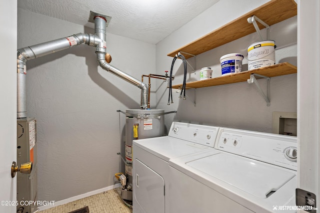 washroom with laundry area, baseboards, washer and clothes dryer, gas water heater, and water heater