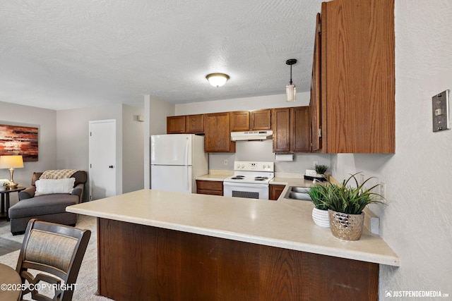 kitchen featuring a peninsula, light countertops, under cabinet range hood, and white appliances