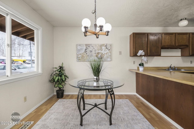 dining room featuring baseboards, light wood-style floors, and an inviting chandelier