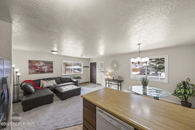 living area featuring a wealth of natural light, a notable chandelier, light carpet, and baseboards