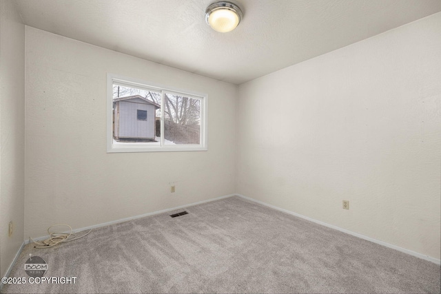 spare room featuring carpet flooring, baseboards, visible vents, and a textured ceiling