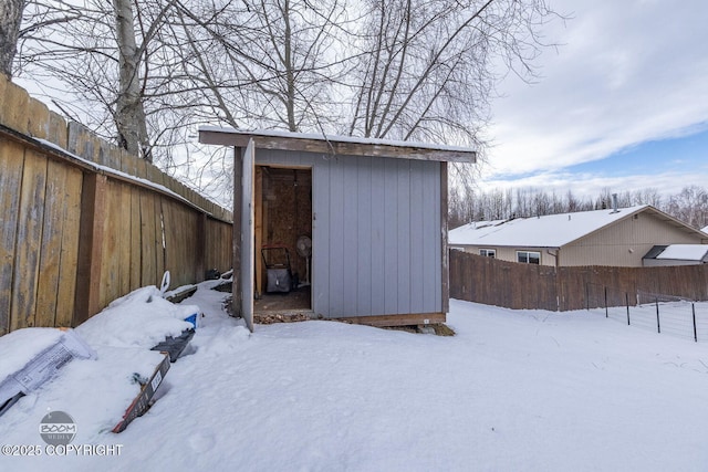 snow covered structure featuring a fenced backyard, a storage shed, and an outdoor structure