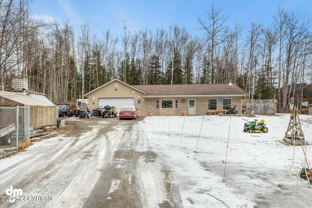 view of front facade with an attached garage, fence, and dirt driveway