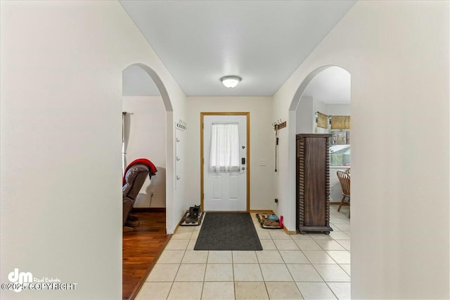 foyer entrance with arched walkways and light tile patterned flooring