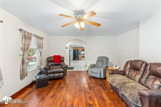 living area with arched walkways, baseboards, a ceiling fan, and hardwood / wood-style floors