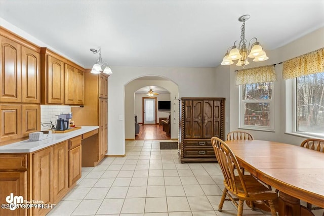 dining area with arched walkways, baseboards, an inviting chandelier, and light tile patterned flooring