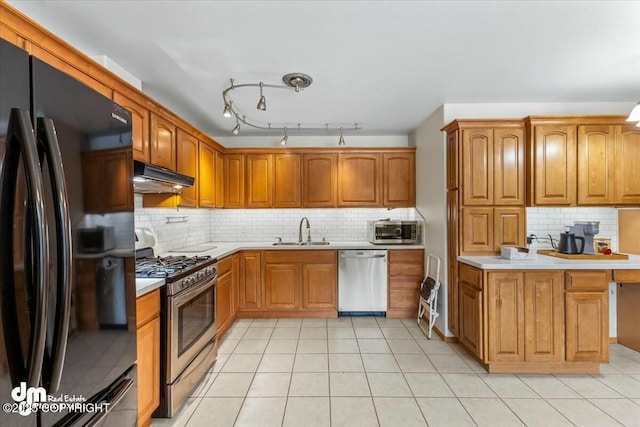 kitchen featuring a sink, light countertops, under cabinet range hood, and stainless steel appliances