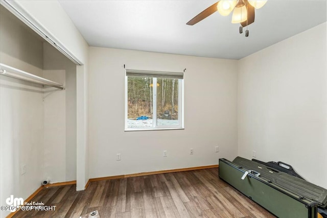 unfurnished bedroom featuring a closet, ceiling fan, baseboards, and wood finished floors