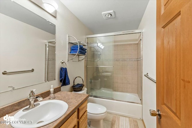 bathroom featuring tile patterned floors, toilet, vanity, and bath / shower combo with glass door