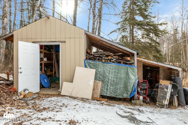 snow covered structure with an outbuilding