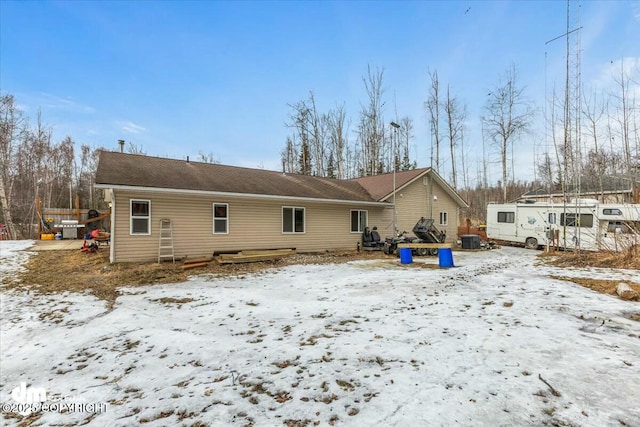 snow covered back of property featuring central AC unit