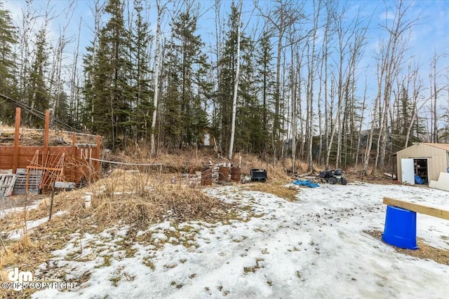 yard layered in snow featuring a storage unit and an outbuilding